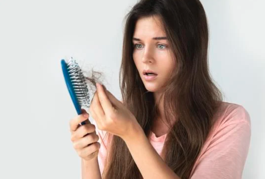 Girl looking at hair brush, looking for best hair loss treatments for females
