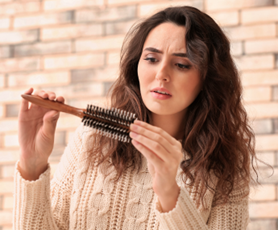Woman studies hair brush, Best Hair Loss Treatments for Females